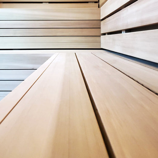 Close-up of slatted sauna bench boards leading toward horizontal wall paneling and backrest boards