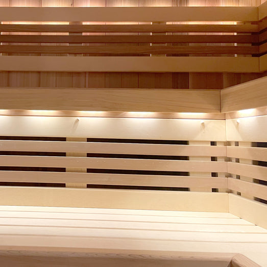 Sauna interior with horizontal wall paneling, open-slat backrests and lit strips under the benches