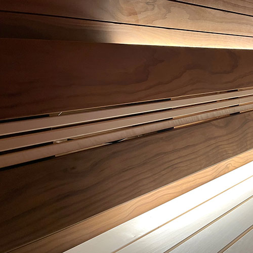 Sauna interior with horizontal wall paneling, warm backlighting along the wall and pale benches in the foreground