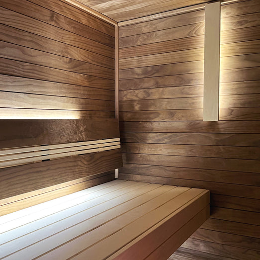 Sauna interior with horizontal wall paneling, two-tier benches and soft lighting along the walls