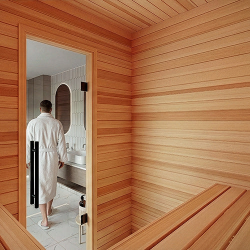 Sauna interior with horizontal wall paneling and benches, a man in a white robe walking out through a glass door