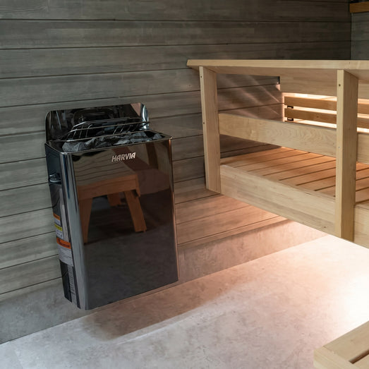 Black Harvia The Wall heater mounted on a gray sauna wall beside wooden benches