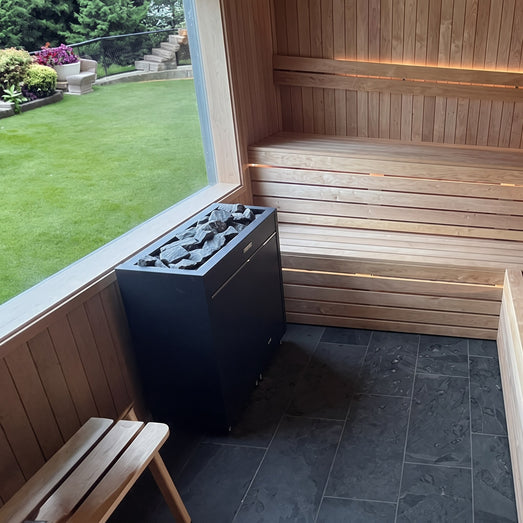 Virta Pro heater in a bright sauna with a picture window overlooking a garden