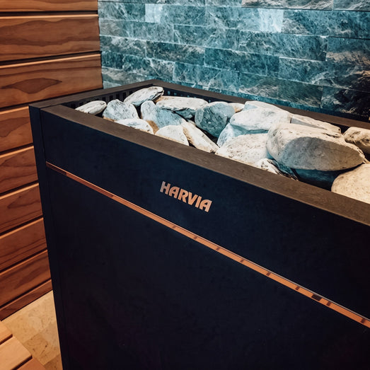 Close-up of the Virta Pro stone bed and copper trim against green tiled sauna wall