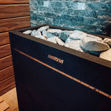 Close-up of the Virta Pro stone bed and copper trim against green tiled sauna wall