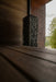 HUUM CLIFF 10.5kW dark-stone heater in a sauna beside a garden-view window