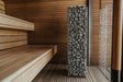 HUUM CLIFF 10.5kW heater standing beside wooden bench in a cedar sauna