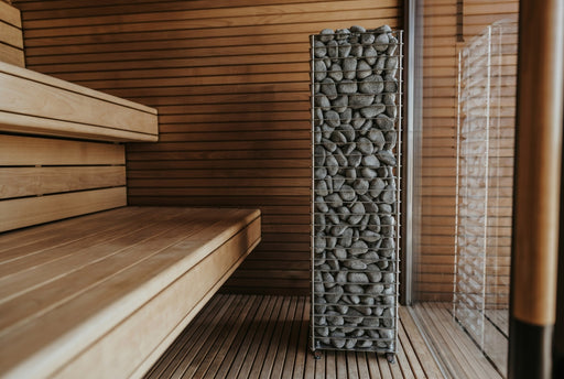 HUUM CLIFF 10.5kW heater standing beside wooden bench in a cedar sauna