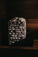 HUUM CLIFF 10.5kW stone heater lit dramatically in a dark wooden sauna