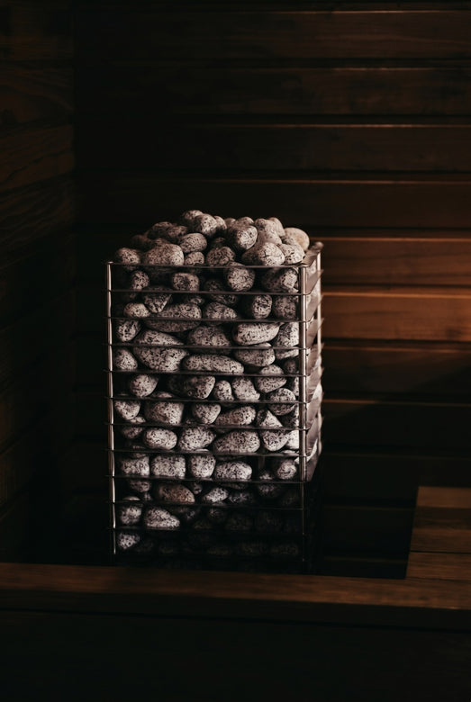 HUUM CLIFF 10.5kW stone heater lit dramatically in a dark wooden sauna
