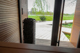 HUUM CLIFF 10.5kW heater in sauna doorway overlooking a green lawn outside
