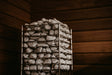HUUM Cliff heater stones glowing under warm light in a cedar sauna corner
