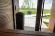 HUUM CLIFF 9kW heater seen through a sauna doorway open to a garden