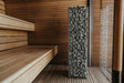 HUUM CLIFF 9kW heater installed beside a wooden bench in a bright sauna