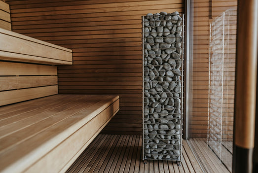 HUUM CLIFF 9kW heater installed beside a wooden bench in a bright sauna