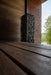 HUUM CLIFF 9kW heater beside a sauna window overlooking green trees