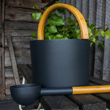 KOLO black sauna bucket and ladle on a rustic bench with birch leaves