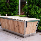 Polar Cold Plunge Tub with cedar slat cover closed on a patio beside tall hedges