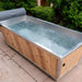 Polar Cold Plunge Tub filled with water on a patio beside green hedges outdoors