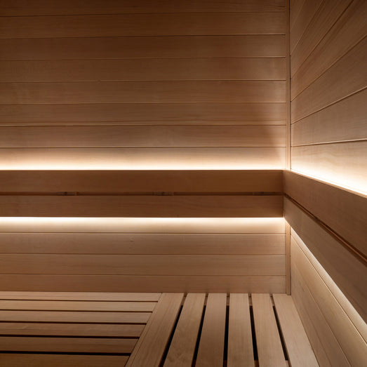Warm-white ProSaunas LED strips under the backrest and bench edge of a light-wood sauna
