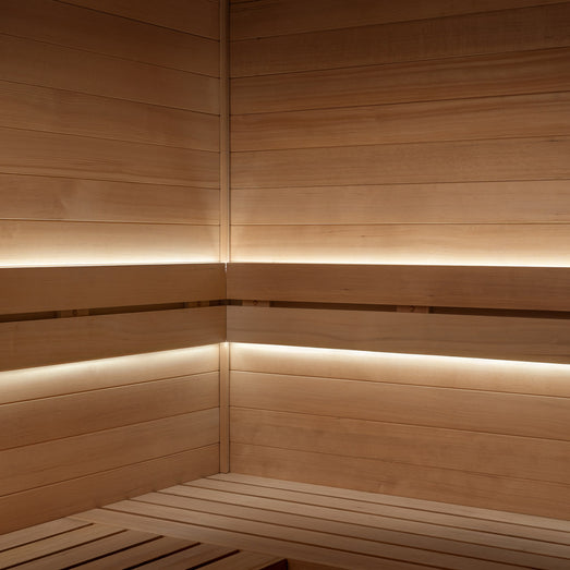 ProSaunas LED strips glowing under two bench tiers in the corner of a wood sauna