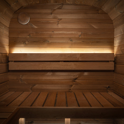 ProSaunas LED strip lighting the backrest of a sauna with a curved wood ceiling