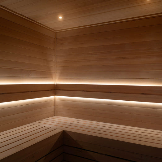Warm-white ProSaunas LED strips along both bench tiers of a corner sauna