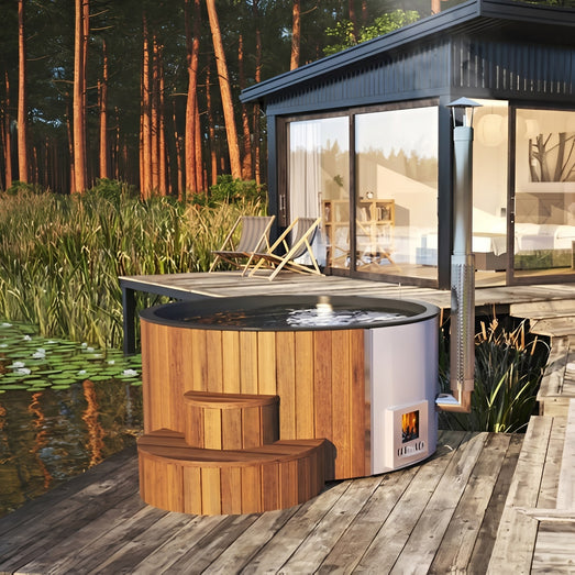 SaunaLife S4 cedar hot tub on a lakeside deck beside a glass cabin with loungers