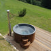 SaunaLife S4 dark-wood hot tub viewed from above on a deck beside a grassy hillside