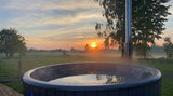 SaunaLife S4 filled hot tub overlooking a misty meadow at sunrise with chimney visible