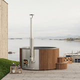 SaunaLife S6 natural-wood hot tub on a coastal deck with firewood basket