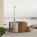 SaunaLife S6 natural-wood hot tub on a coastal deck with firewood basket