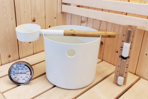 SaunaLife white bucket, ladle, thermometer and sand timer accessory set on a bench