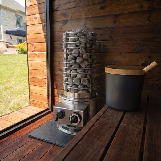 SaunaLife Titan SL1 installed in a wooden sauna on a stone floor tile beside a sauna bucket
