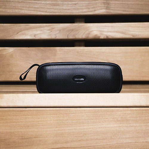 SaunaLife Verse speaker lying on a sauna bench with its carry strap