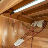 SaunaLumin LED strip wired to a labeled power driver and junction box behind cedar paneling