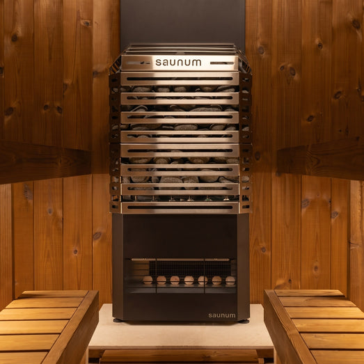 Saunum Air 5 heater between cedar benches against warm wood sauna walls, front view