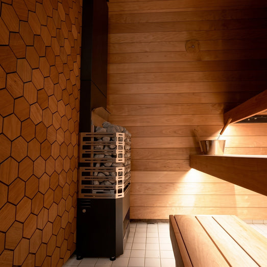 Saunum Air 5 heater in a lit sauna interior with hexagon wall and tiered benches
