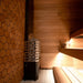 Saunum Air heater beside a honeycomb wood-tiled wall in a cozy sauna