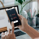 Hand using Saunum smartphone app showing 19:30 timer and 100C temperature controls