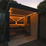 Saunum Air heater in a modern outdoor backyard sauna lit warmly at dusk