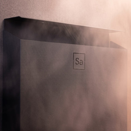 Top corner detail of the black Saunum Air heater with steam rising around it