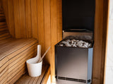 Saunum Air L 10 heater filled with stones beside a white bucket in a cedar sauna