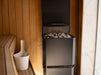 Saunum Air L 10 heater and ladle bucket in a cedar sauna beside a marble wall