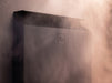 Top corner detail of the black Saunum Air L 10 heater with steam rising in soft light