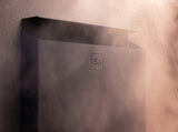 Top corner detail of the black Saunum Air L 10 heater with steam rising in soft light