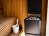 Saunum Air L 13 heater with sauna stones installed beside cedar benches and a water bucket