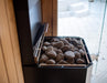 Close-up of the Saunum Air L 13 heater stone tray filled with rounded sauna stones