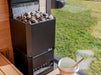 Saunum Air L 13 heater filled with stones in a sauna with a window overlooking a green lawn
