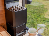 Saunum Air L 13 heater filled with stones in a sauna with a window overlooking a green lawn